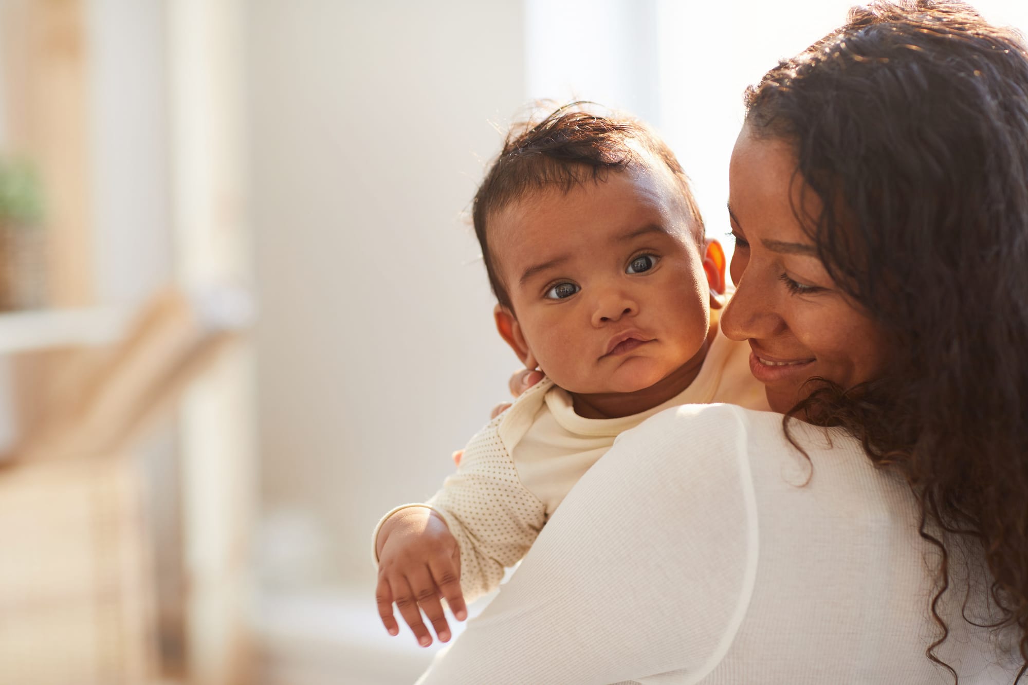 A smiling mother holding her baby over her shoulder