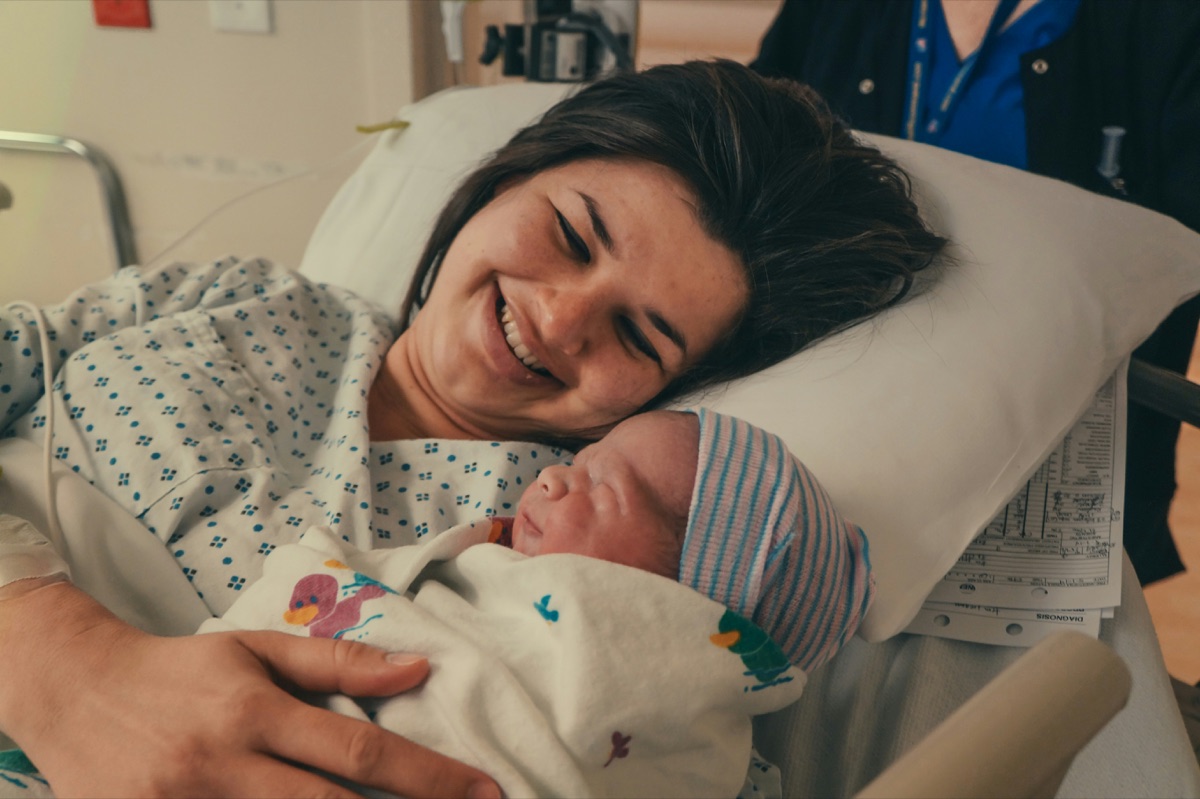 A new parent holding their baby in a hospital bed, smiling
